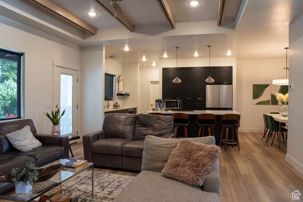 Living room featuring light wood-type flooring, beam ceiling, and recessed lighting