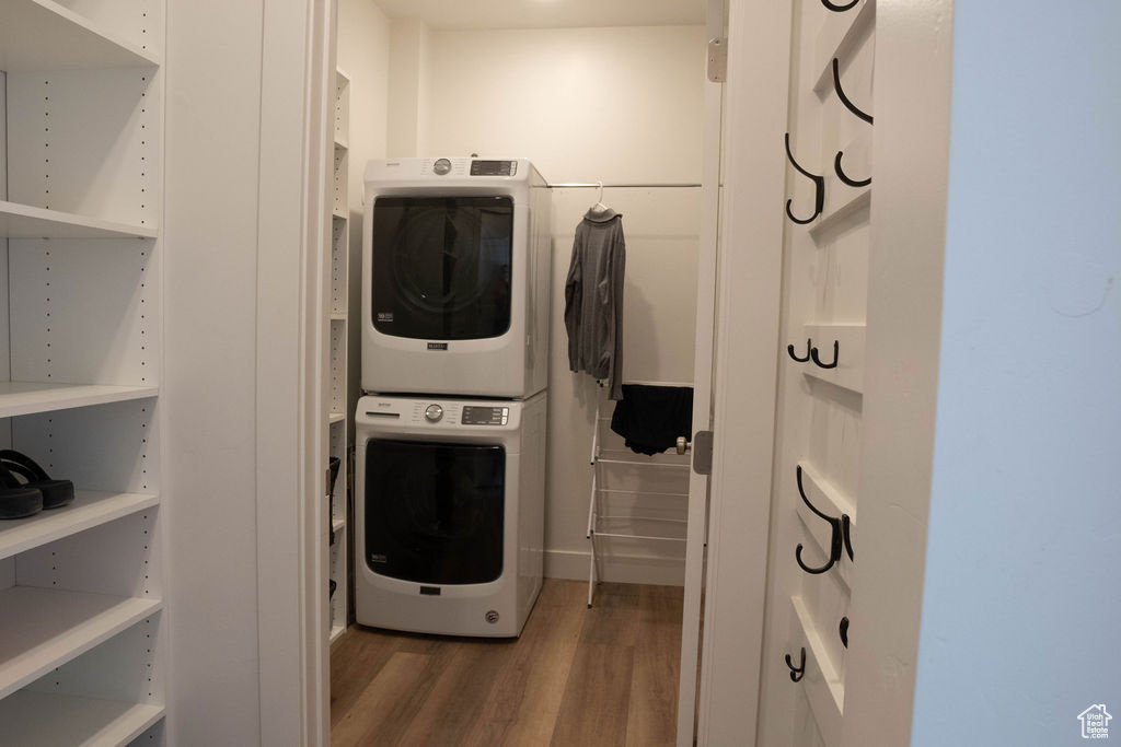 Laundry room with stacked washing machine and dryer and wood finished floors