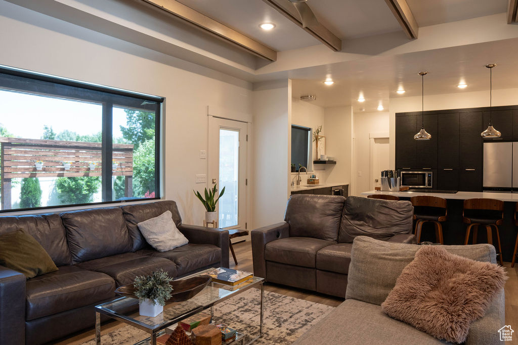 Living area with beam ceiling, light wood-style flooring, and recessed lighting