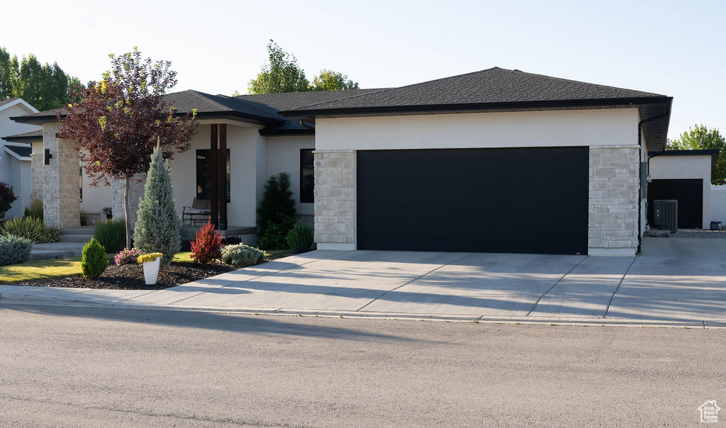 View of front facade featuring stone siding, concrete driveway, and stucco siding