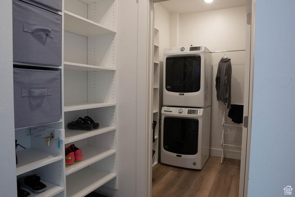 Laundry area featuring stacked washing machine and dryer and wood finished floors