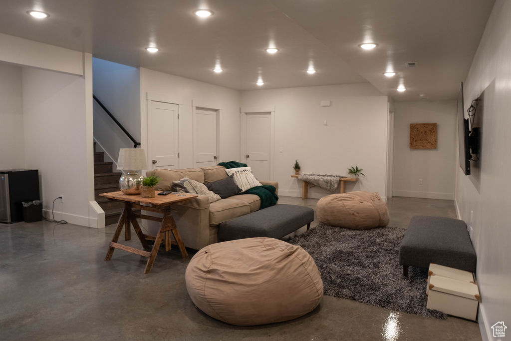 Living area featuring finished concrete flooring, stairway, and recessed lighting