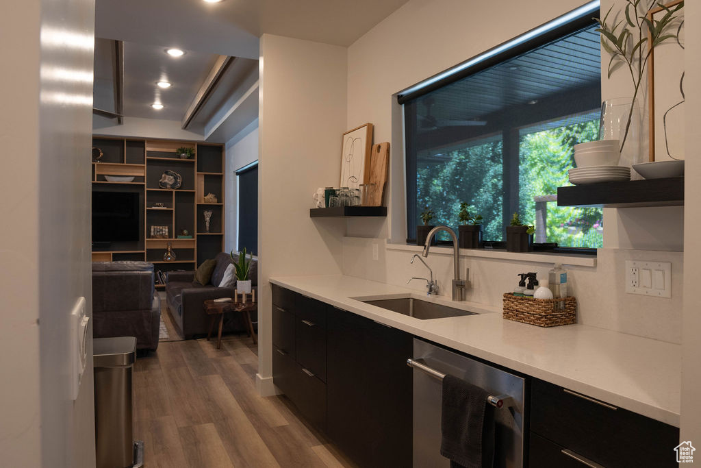 Kitchen featuring dark cabinets, modern cabinets, dark wood-style floors, stainless steel dishwasher, and light countertops