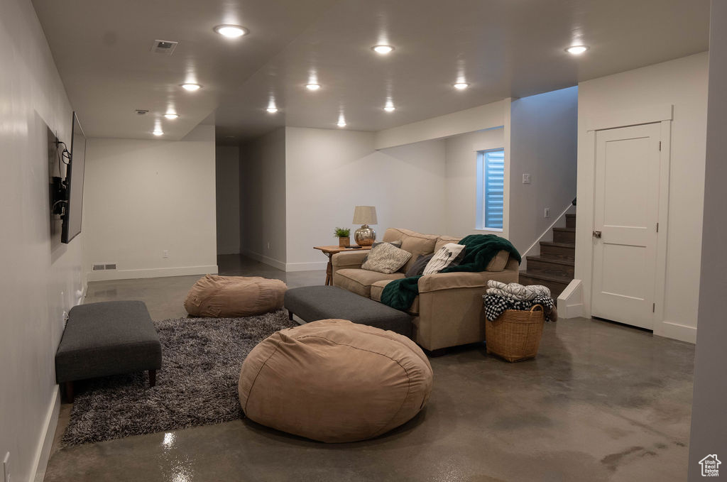Living room featuring finished concrete floors, stairs, and recessed lighting