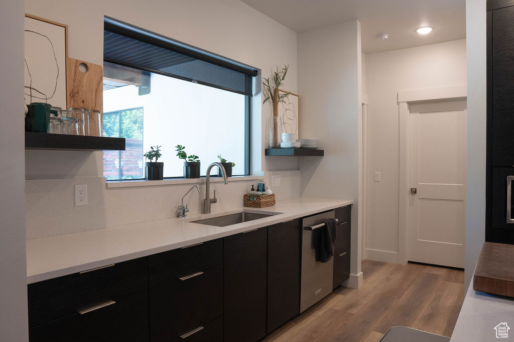 Kitchen with dark cabinets, open shelves, light wood-type flooring, modern cabinets, and dishwasher