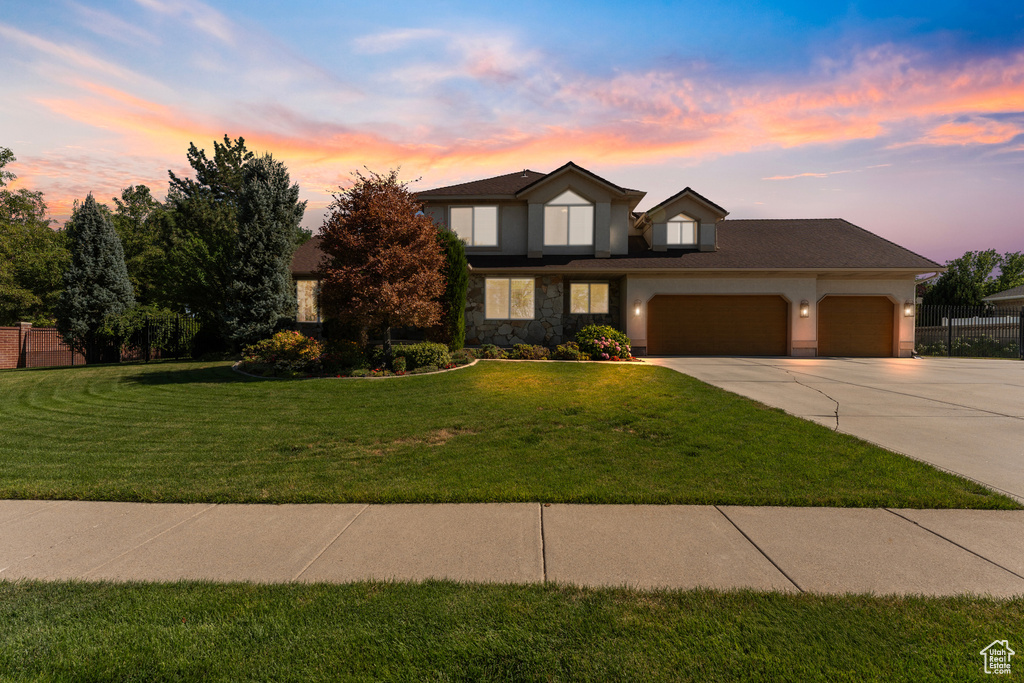 Traditional-style home featuring an attached garage, driveway, and stone siding