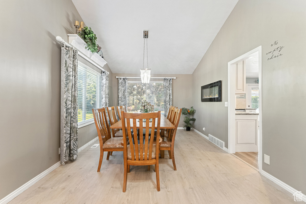 Dining area featuring a chandelier, lofted ceiling, and light wood-style flooring
