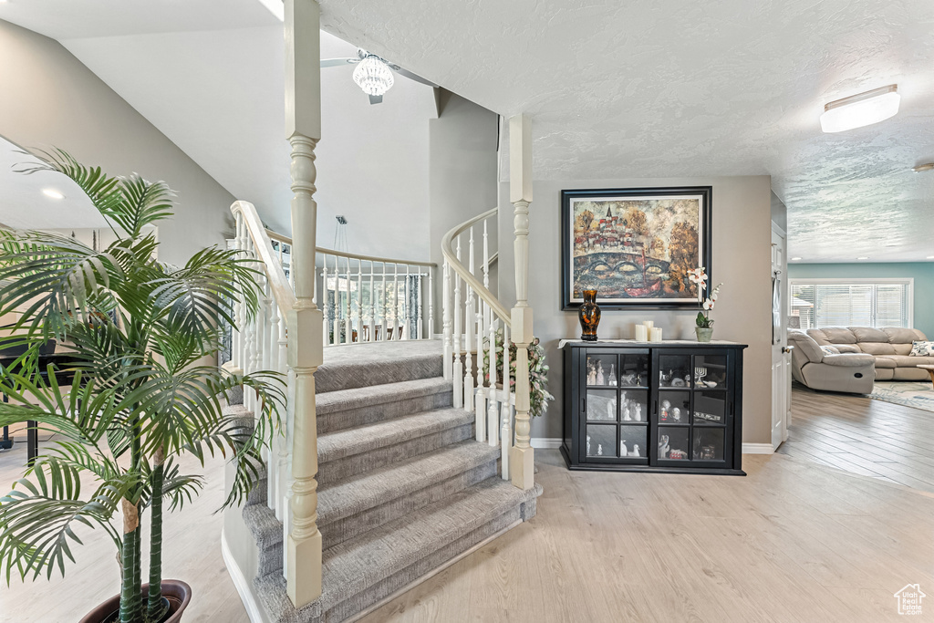 Staircase with wood finished floors and a textured ceiling