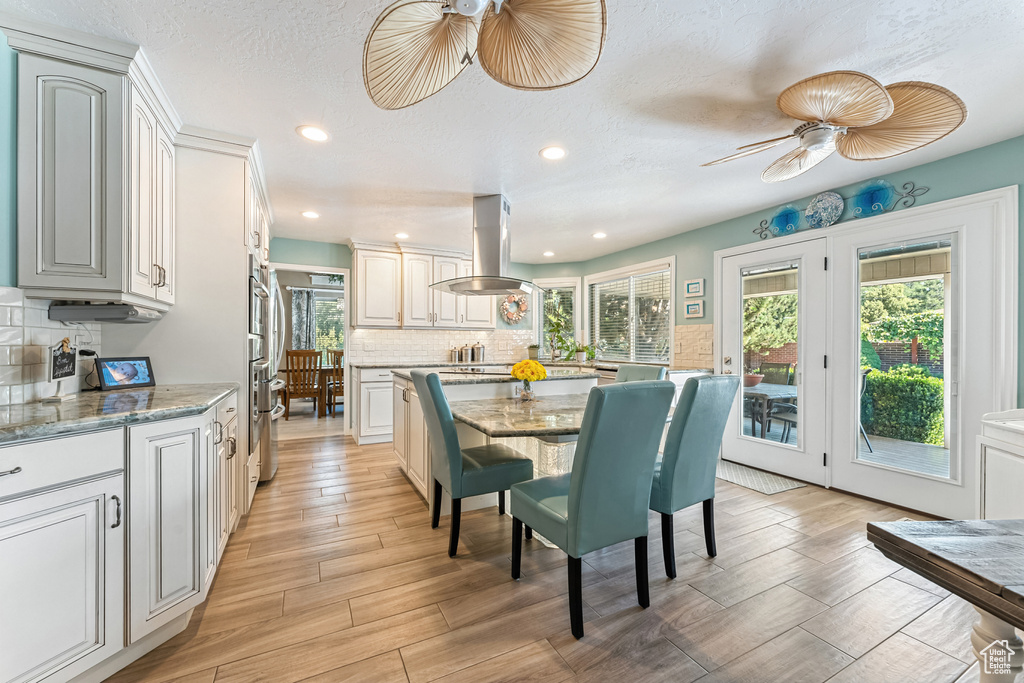 Dining space featuring plenty of natural light, light wood-type flooring, recessed lighting, a ceiling fan, and a textured ceiling