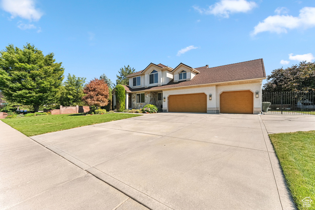 Traditional-style home with a garage, driveway, stone siding, and stucco siding