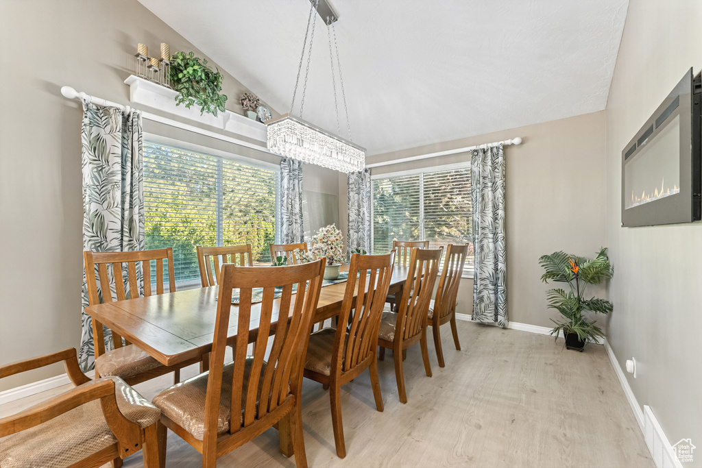 Dining space with light wood finished floors, vaulted ceiling, and a chandelier