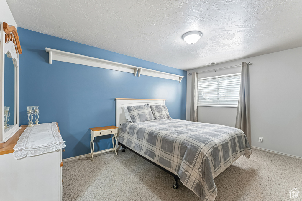 Carpeted bedroom with a textured ceiling and baseboards