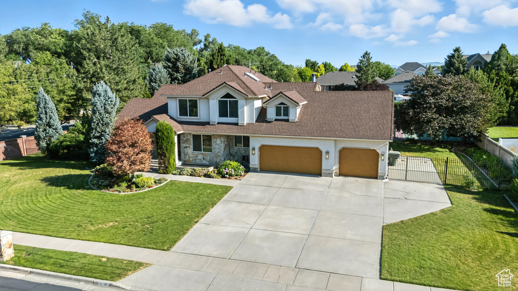Traditional-style home featuring a gate, an attached garage, stone siding, driveway, and stucco siding