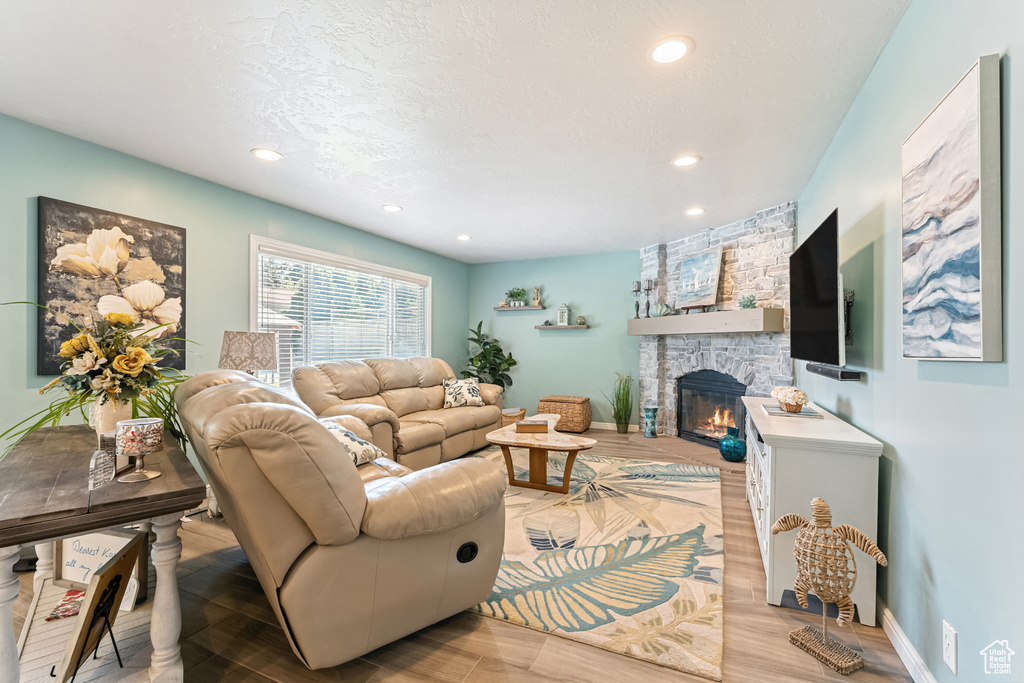 Living area featuring a stone fireplace, wood finished floors, and recessed lighting