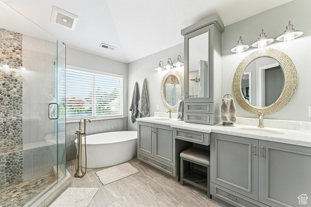 Full bathroom featuring double vanity, a freestanding tub, a stall shower, and vaulted ceiling