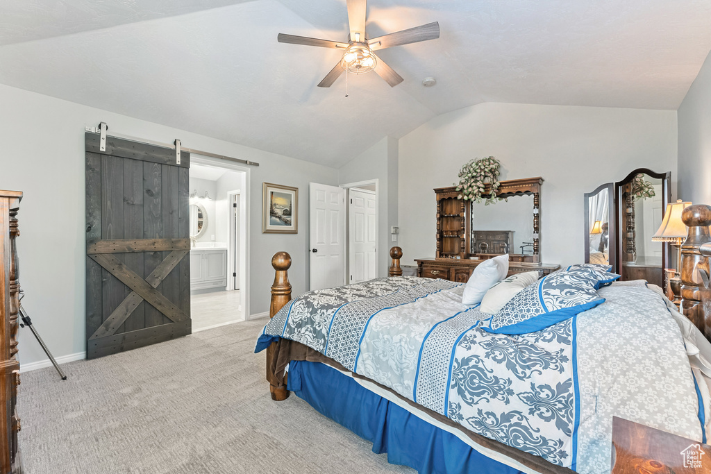 Bedroom with a barn door, lofted ceiling, carpet, ceiling fan, and ensuite bathroom