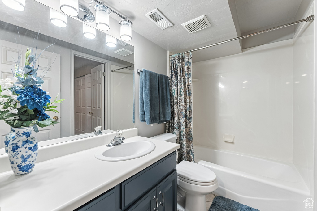 Bathroom with vanity, shower / tub combo, and tile patterned flooring