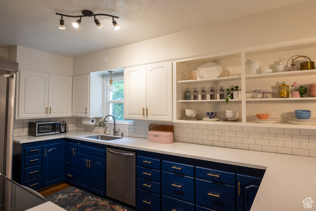Kitchen featuring white cabinetry, stainless steel appliances, blue cabinetry, a textured ceiling, and decorative backsplash