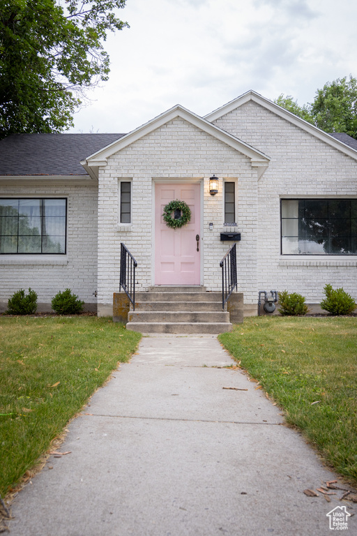 View of front facade featuring entry steps, a front yard, and brick siding