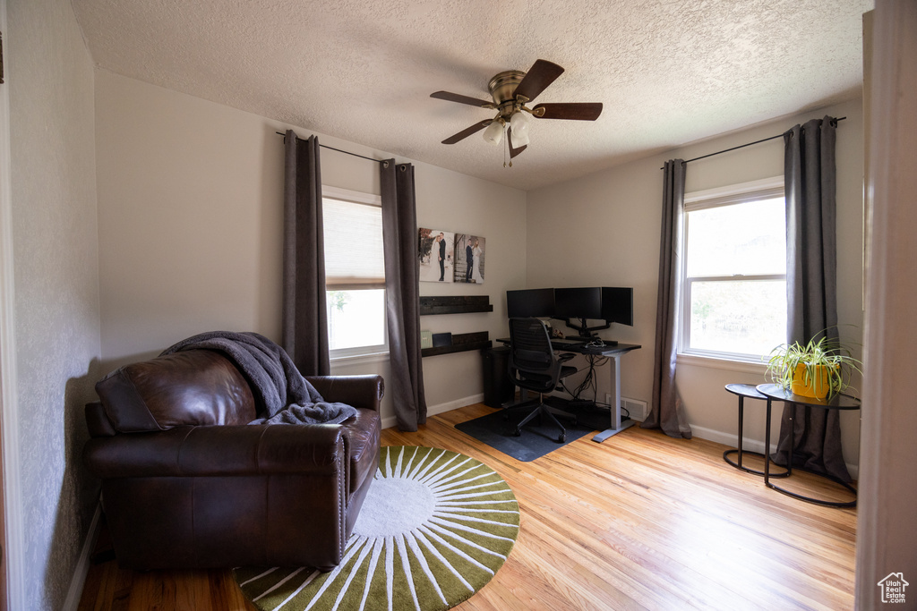 Living area with a desk, wood finished floors, ceiling fan, and a textured ceiling