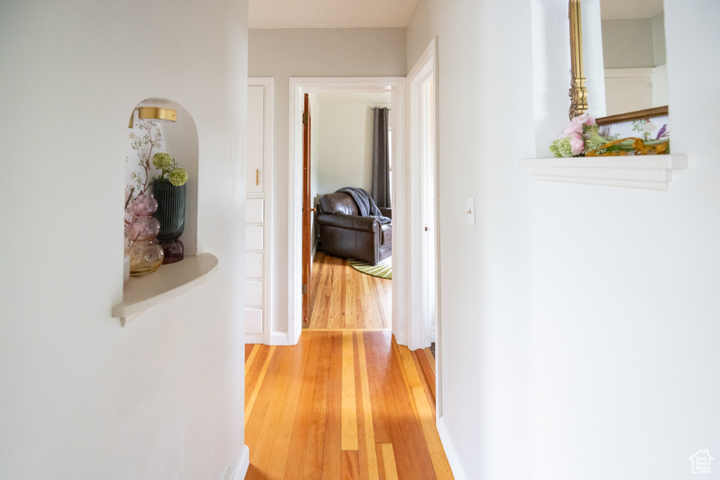 Hall featuring light wood finished floors and arched walkways