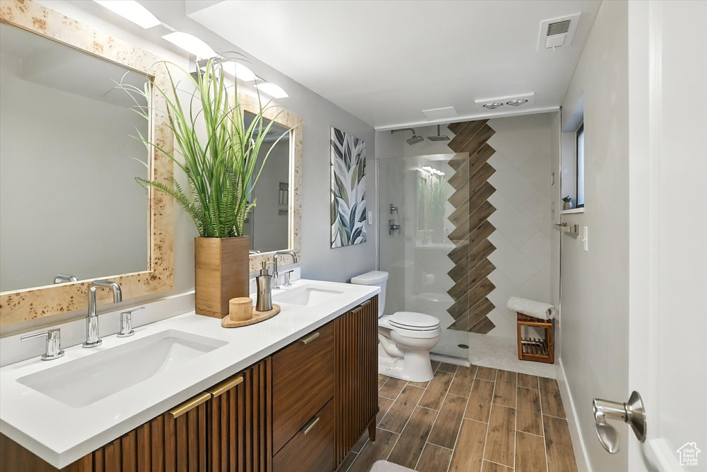 Full bathroom with double vanity, wood finish floors, and walk in shower