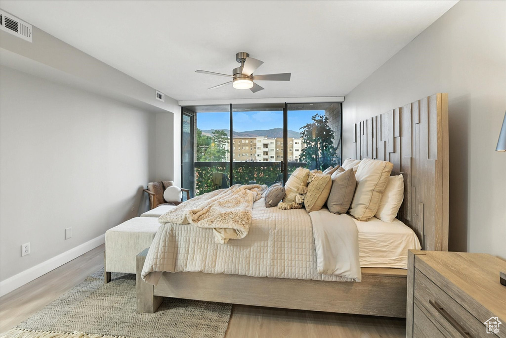 Bedroom featuring expansive windows, wood finished floors, and a ceiling fan