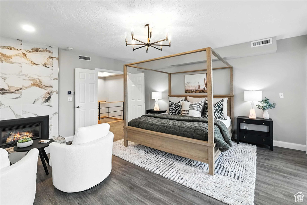 Bedroom with a chandelier, wood finished floors, and a premium fireplace