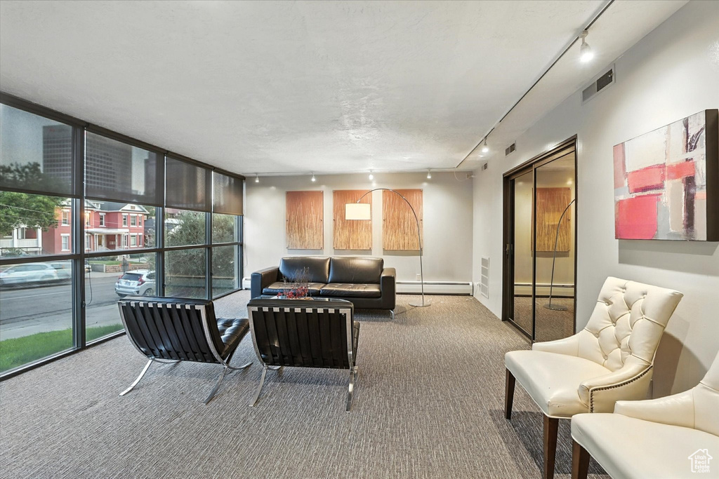 Living room with rail lighting, floor to ceiling windows, carpet flooring, plenty of natural light, and baseboard heating