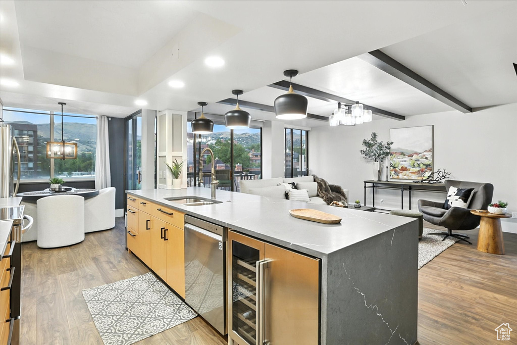 Kitchen featuring beverage cooler, open floor plan, light wood-type flooring, appliances with stainless steel finishes, and light countertops