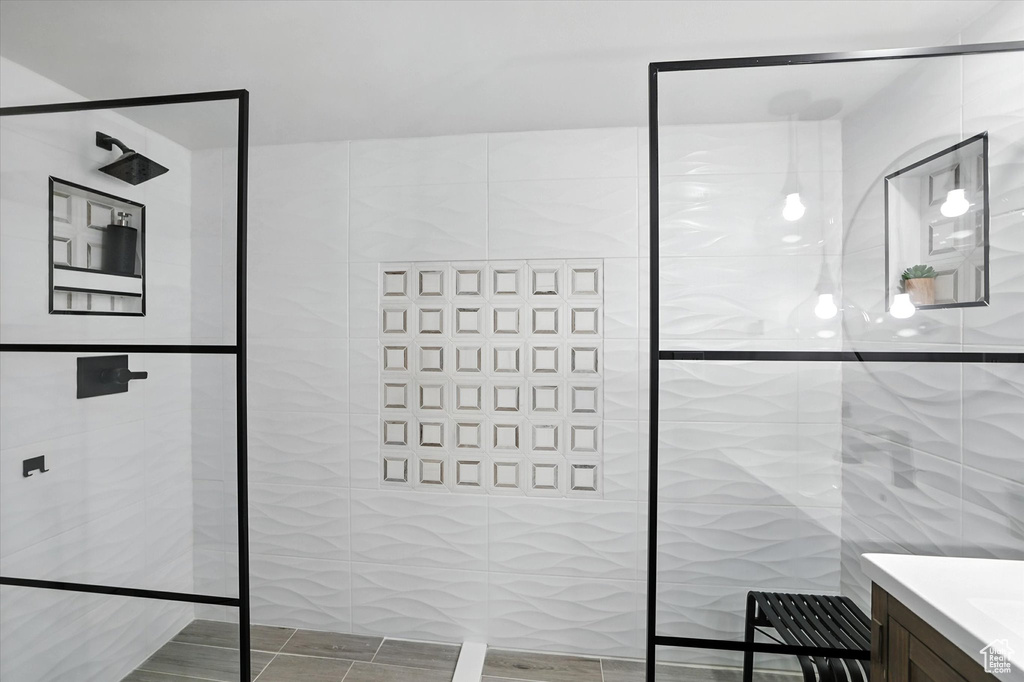 Bathroom with tile walls, walk in shower, and vanity
