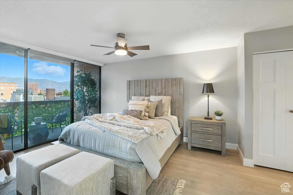 Bedroom with floor to ceiling windows, light wood finished floors, access to outside, and ceiling fan