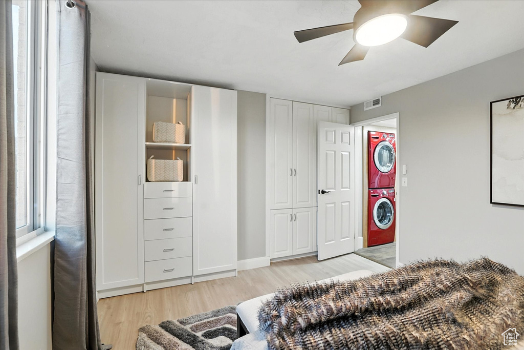 Bedroom featuring estacked washer and dryer, light wood-style flooring, and a ceiling fan