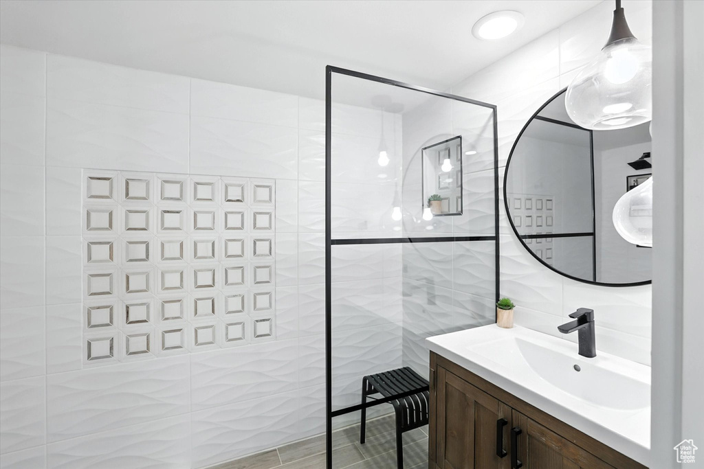 Full bath with tile walls, vanity, and walk in shower