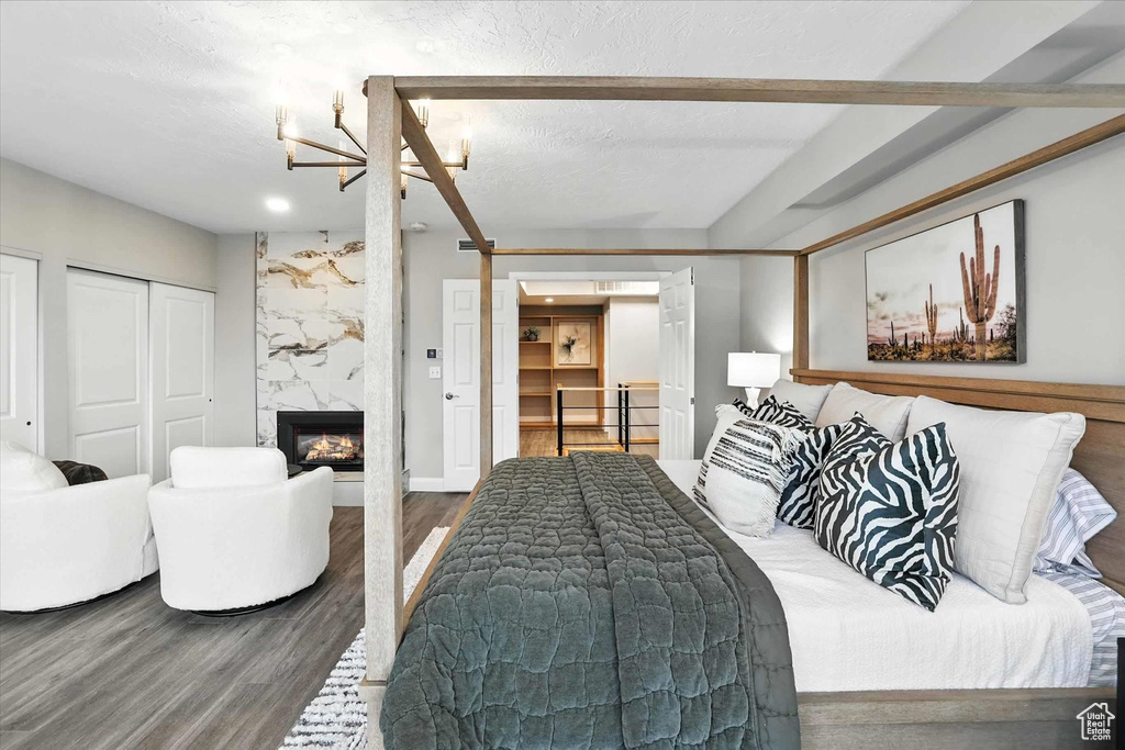 Bedroom with wood finished floors, a high end fireplace, and a chandelier