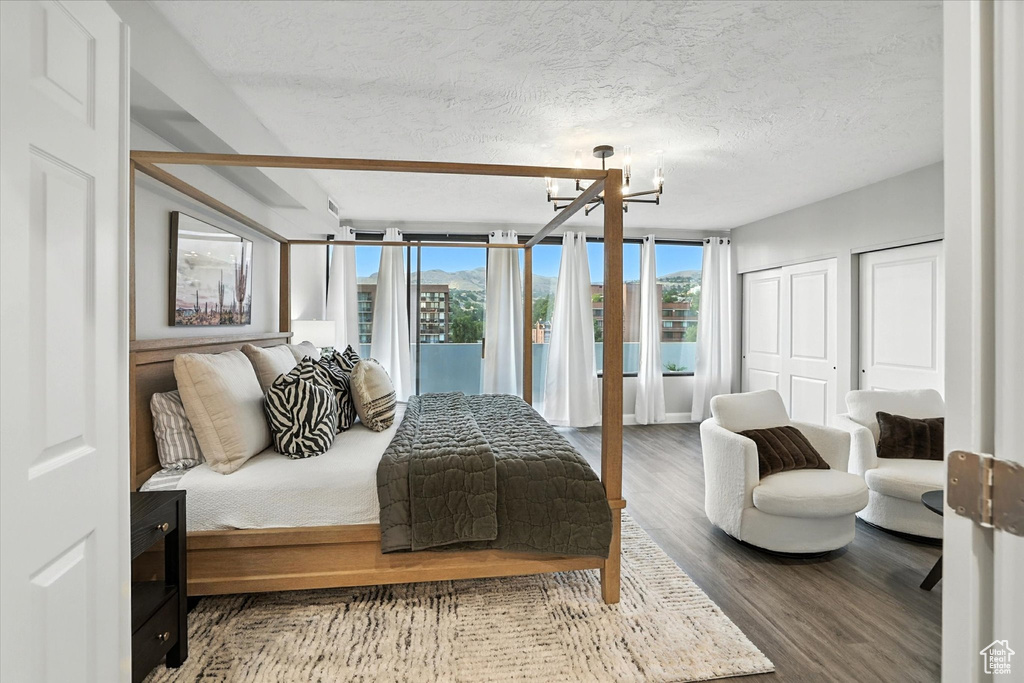 Bedroom featuring a chandelier, wood finished floors, multiple closets, and a textured ceiling