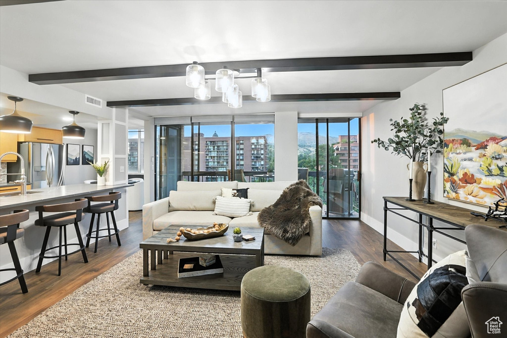 Living area with beam ceiling, wood finished floors, and a city view