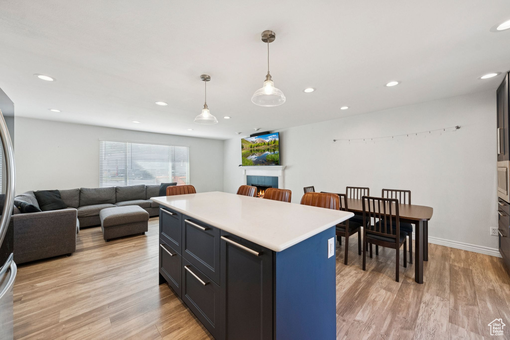 Kitchen featuring light wood-type flooring, light countertops, a center island, recessed lighting, and open floor plan