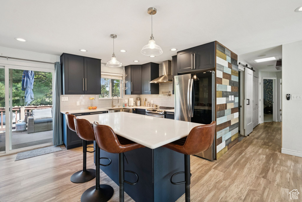 Kitchen with light wood-type flooring, light countertops, a kitchen breakfast bar, appliances with stainless steel finishes, and recessed lighting