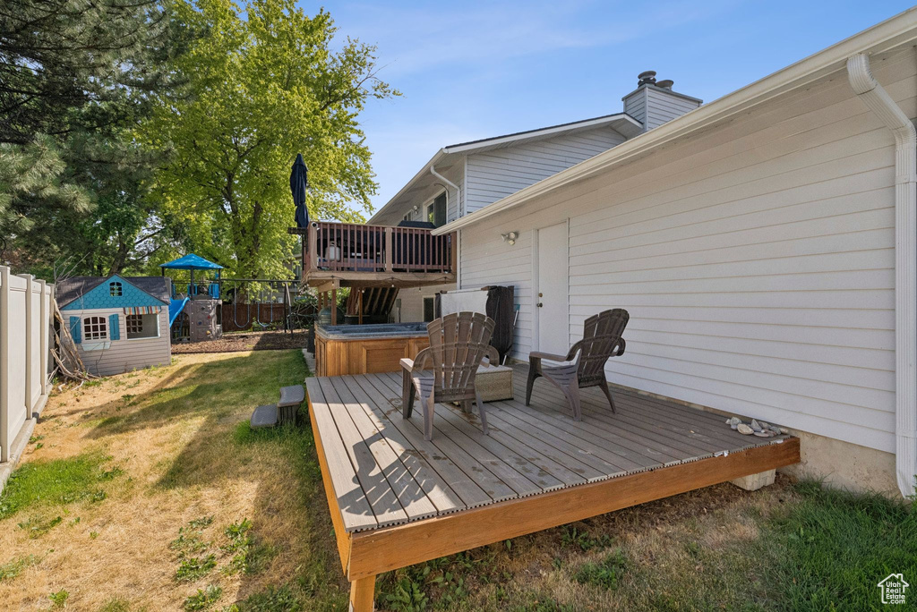 Wooden deck with a hot tub, a fenced backyard, and a storage unit