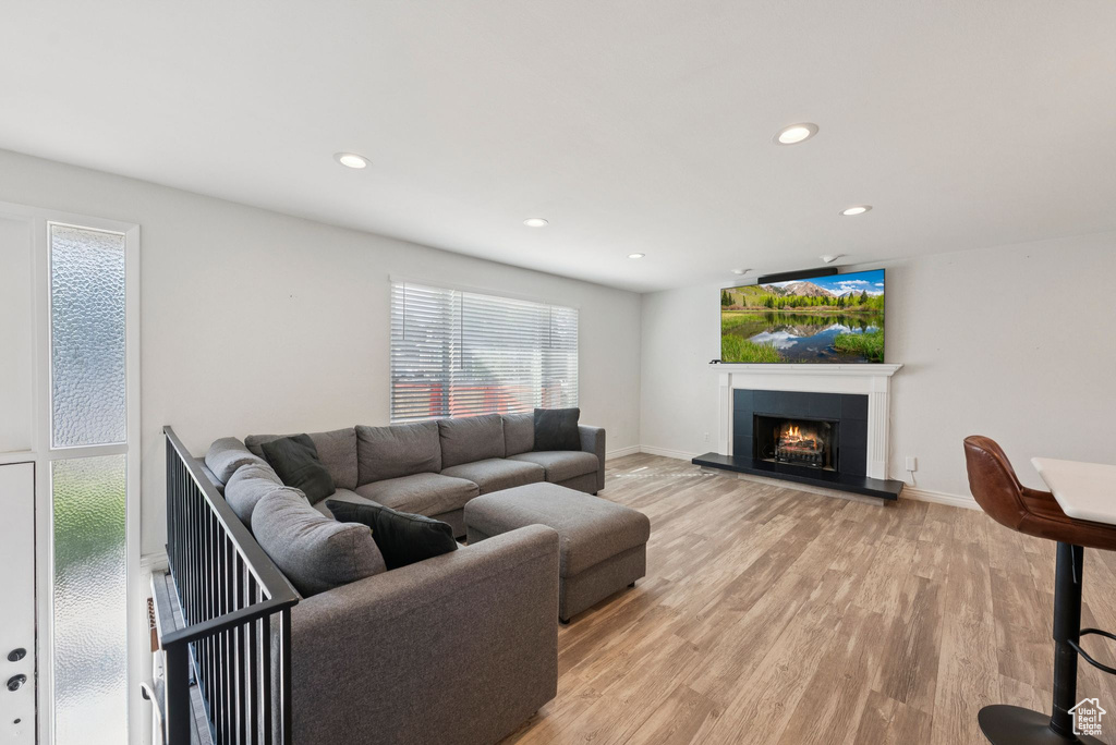 Living room with light wood-type flooring, a tile fireplace, and recessed lighting