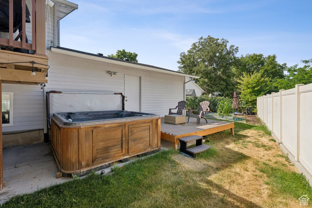 Wooden terrace featuring a hot tub and a fenced backyard