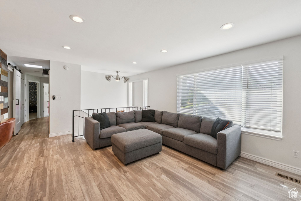 Living room with light wood-style floors, recessed lighting, and a barn door
