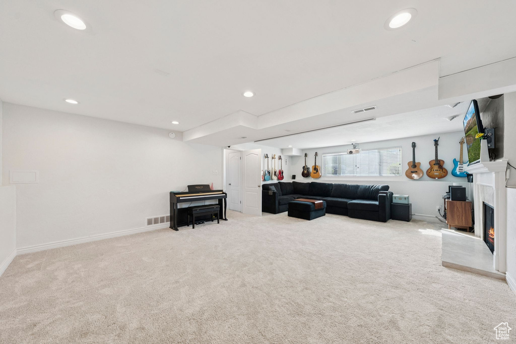 Living room with carpet, recessed lighting, and a warm lit fireplace