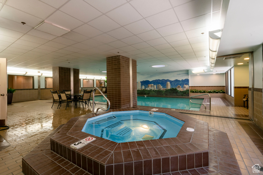 Indoor community pool featuring an in-ground hot tub