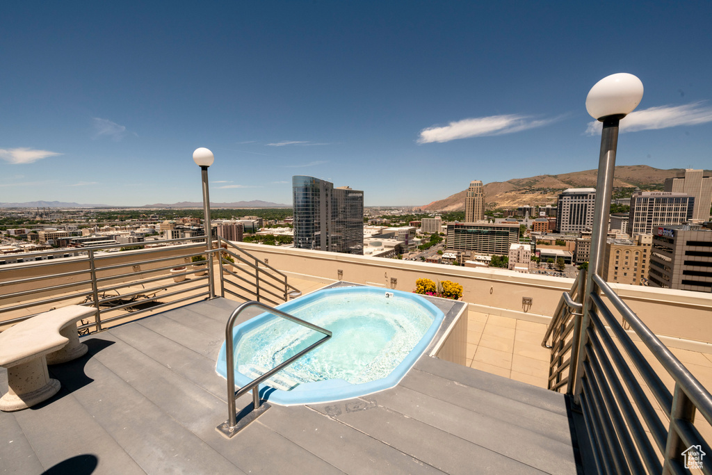 Wooden terrace featuring a mountain view, a city view, and an in-ground hot tub
