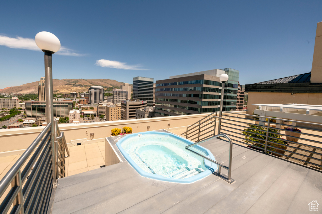 Balcony featuring an outdoor hot tub, a mountain view, and a view of city