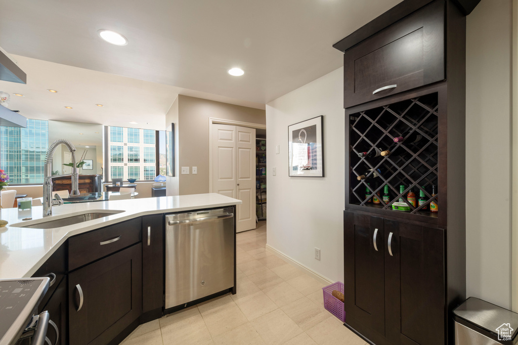 Kitchen featuring stainless steel dishwasher, light countertops, recessed lighting, range, and dark brown cabinets