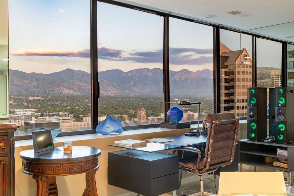 Home office featuring a mountain view, floor to ceiling windows, and a view of city