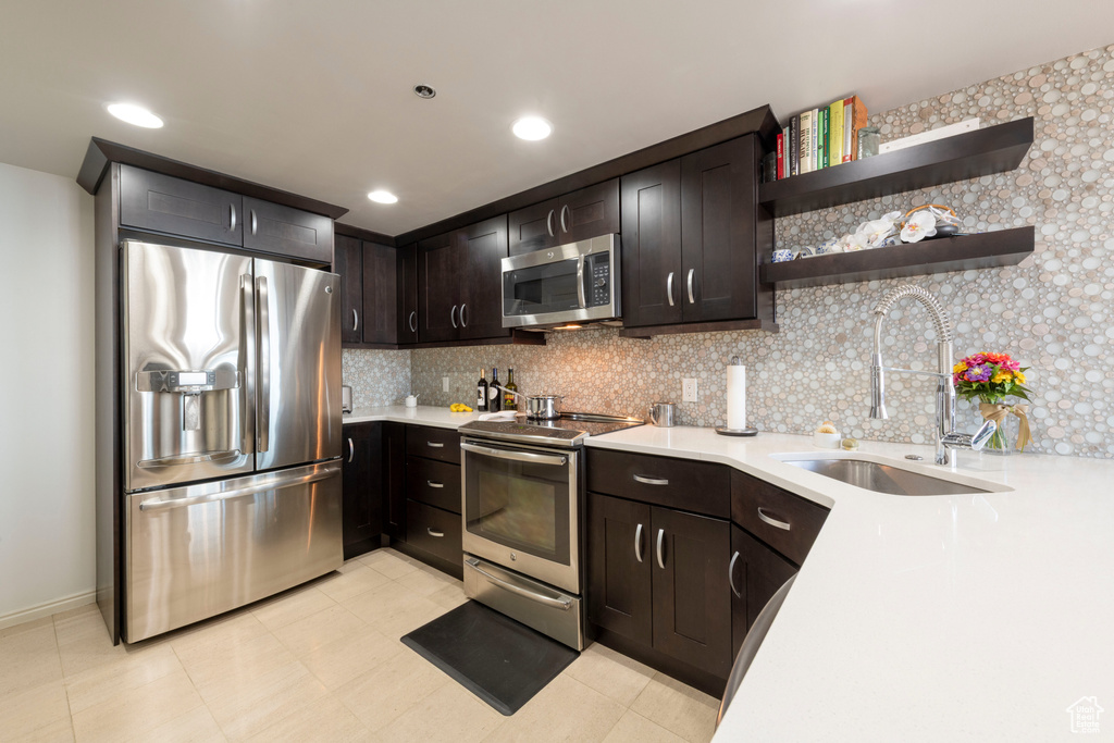 Kitchen with stainless steel appliances, light countertops, decorative backsplash, and recessed lighting
